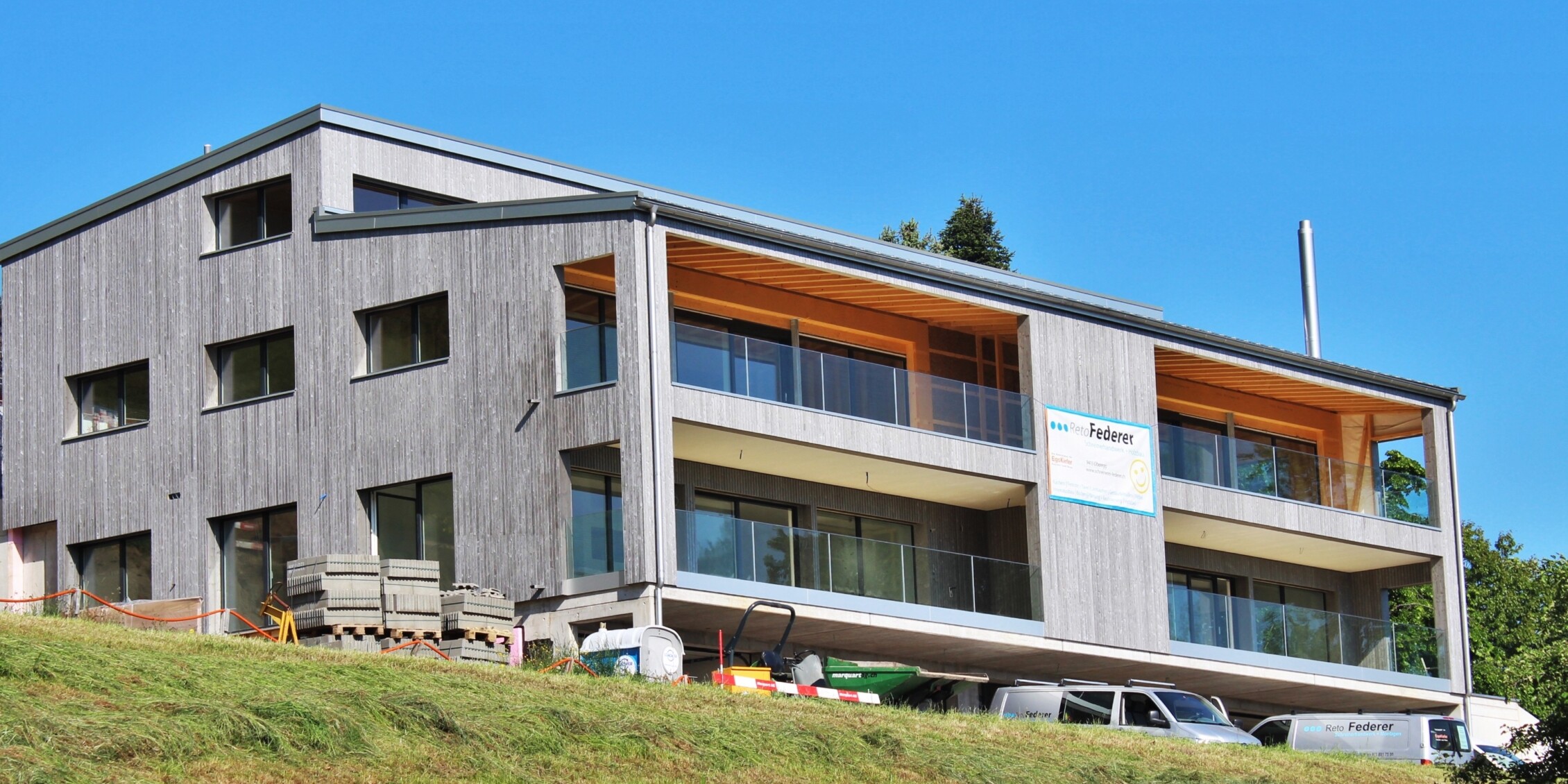 Die Wohnüberbauung im Weiler Zelg in Wolfhalden: Holzbau mit senkrechter Schalung und gedeckten Balkonen am Hang